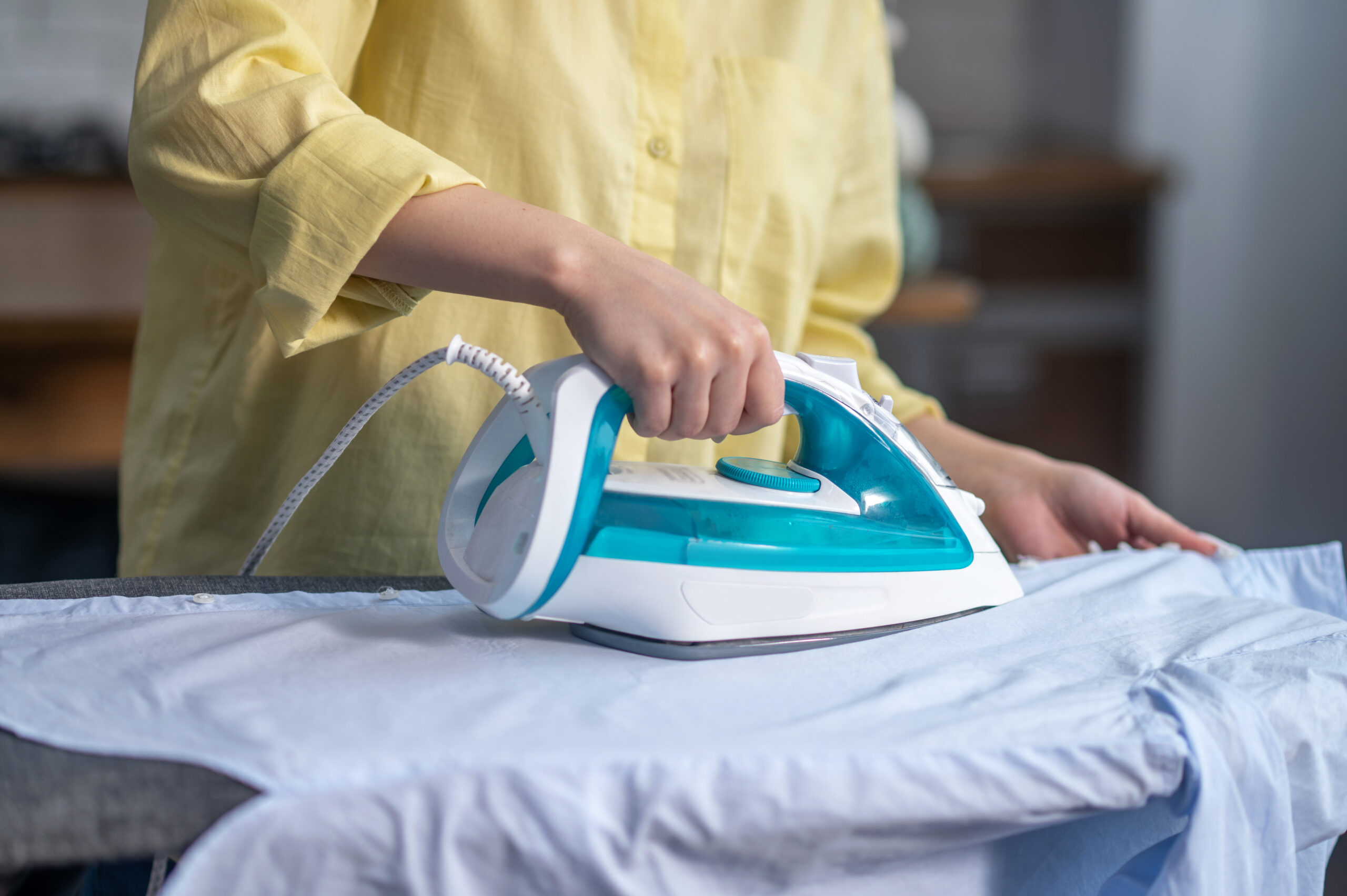 female hands ironing wrinkled clothes on the ironing board