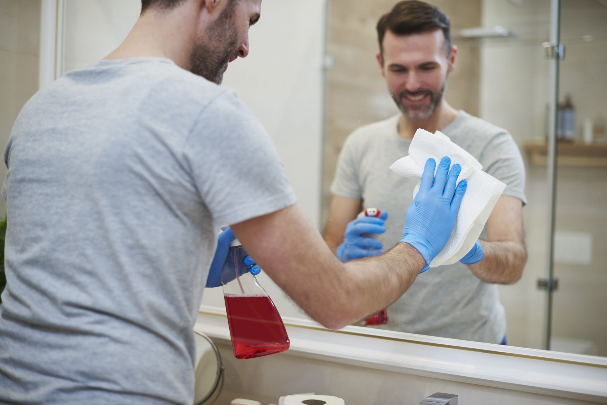 rear view of man cleaning mirror in the bathroom