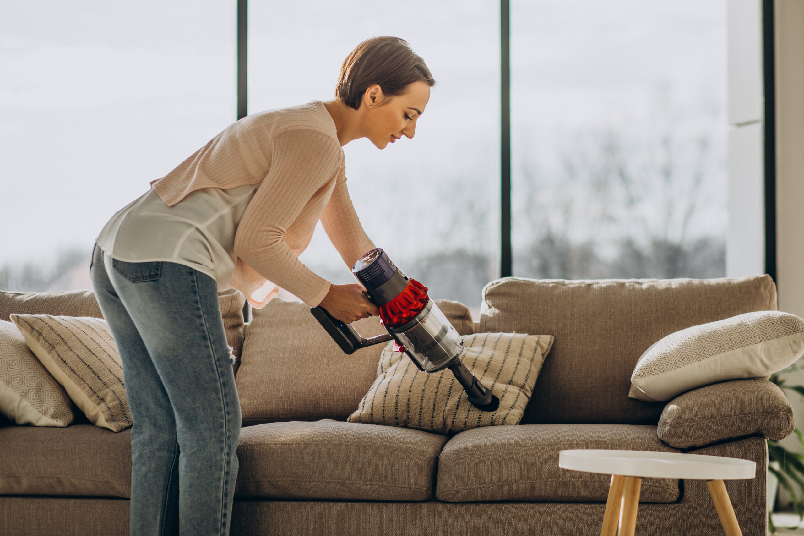 young woman with rechargeable vacuum cleaner cleaning at home